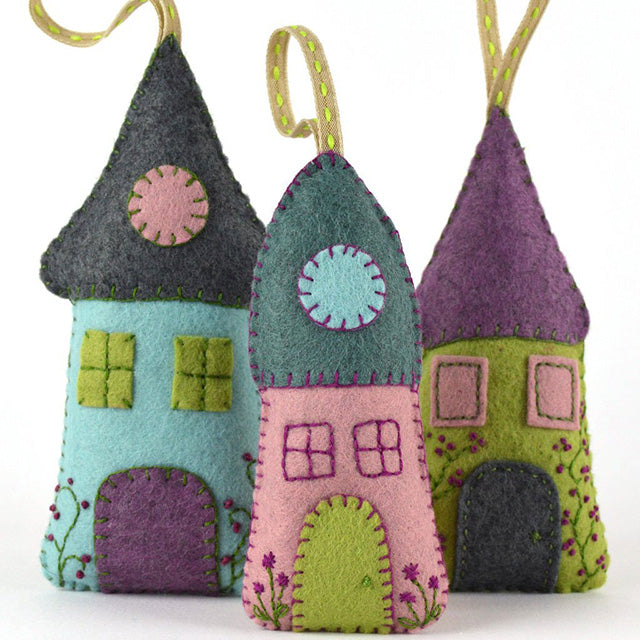 Colorful felt houses with green, purple, and blue roofs arranged together on a flat surface.