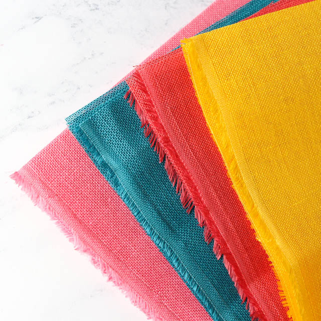 1. Four vibrant cloths with fringes, showcasing a variety of colors and patterns, arranged neatly together.
