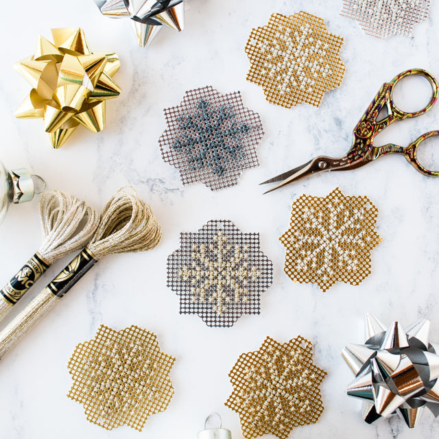 Six skeins of metallic embroidery floss on a marble surface with text: HOW TO CROSS STITCH WITH METALLIC THREAD
