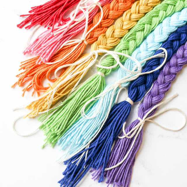 A vibrant display of colored yarns with tassels arranged in a rainbow pattern.