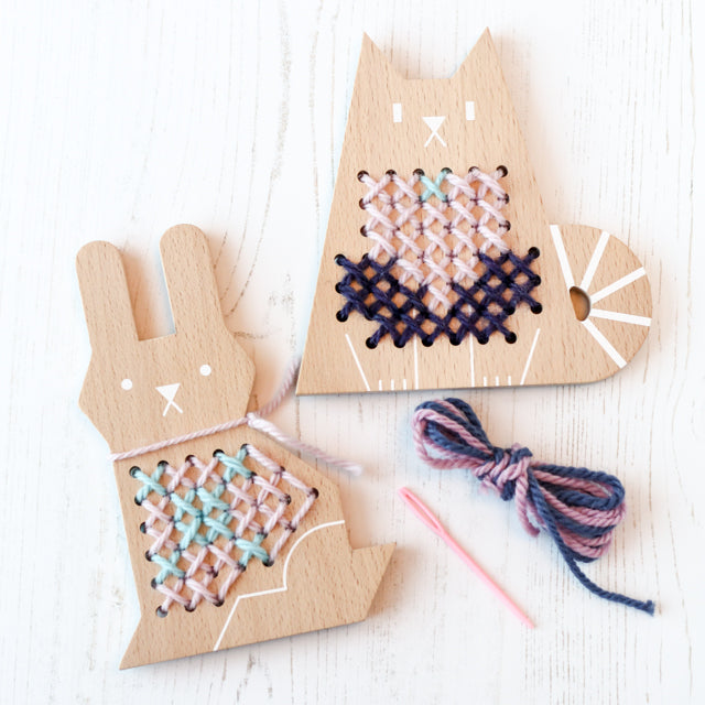 Wooden rabbit and cat shapes with partial cross-stitch embroidery, plus a needle and yarn bundle.