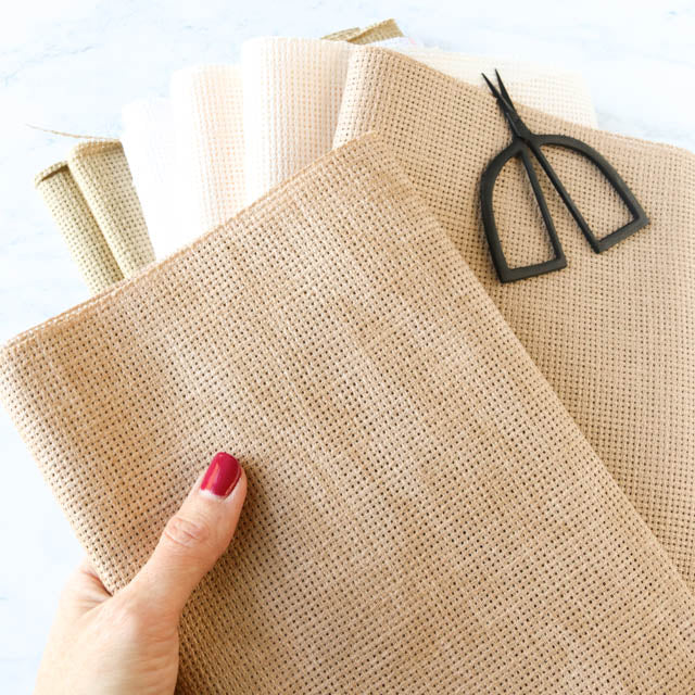 A person holding a piece of fabric in one hand and scissors in the other, preparing to cut the fabric.