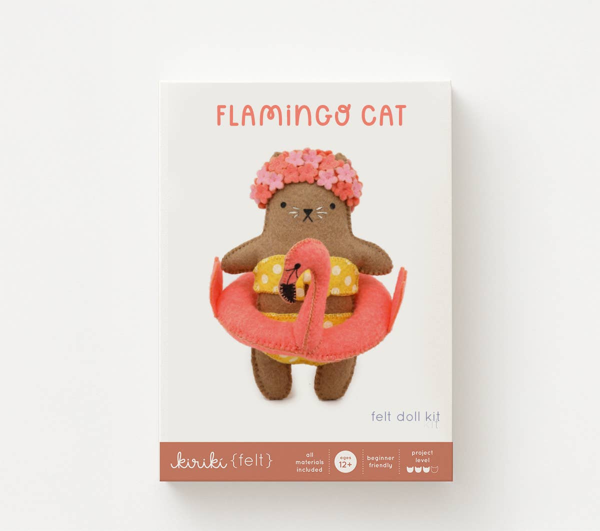 Felt doll kit packaging with a brown cat-like character wearing a swimsuit and flamingo float, on a white background.