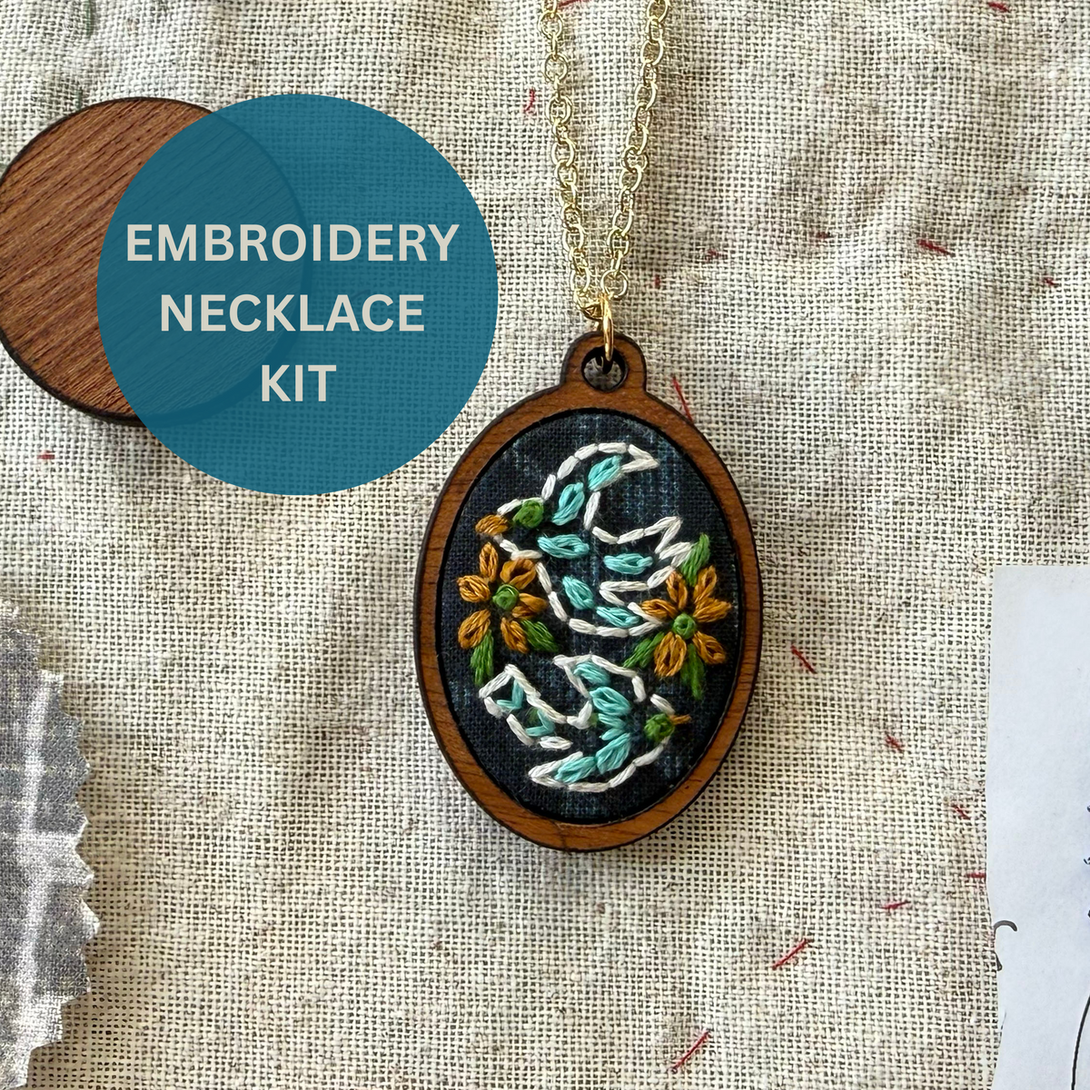 Embroidery necklace kit with wooden pendant and embroidered design on fabric background