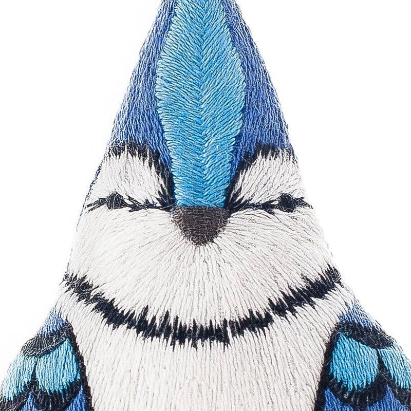 Embroidered patch of a blue jay bird on a white background