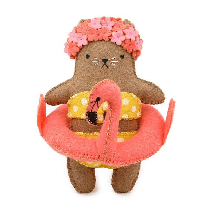 Stuffed animal toy resembling a cat in a swimsuit with a pink flamingo float and flower crown on a white background