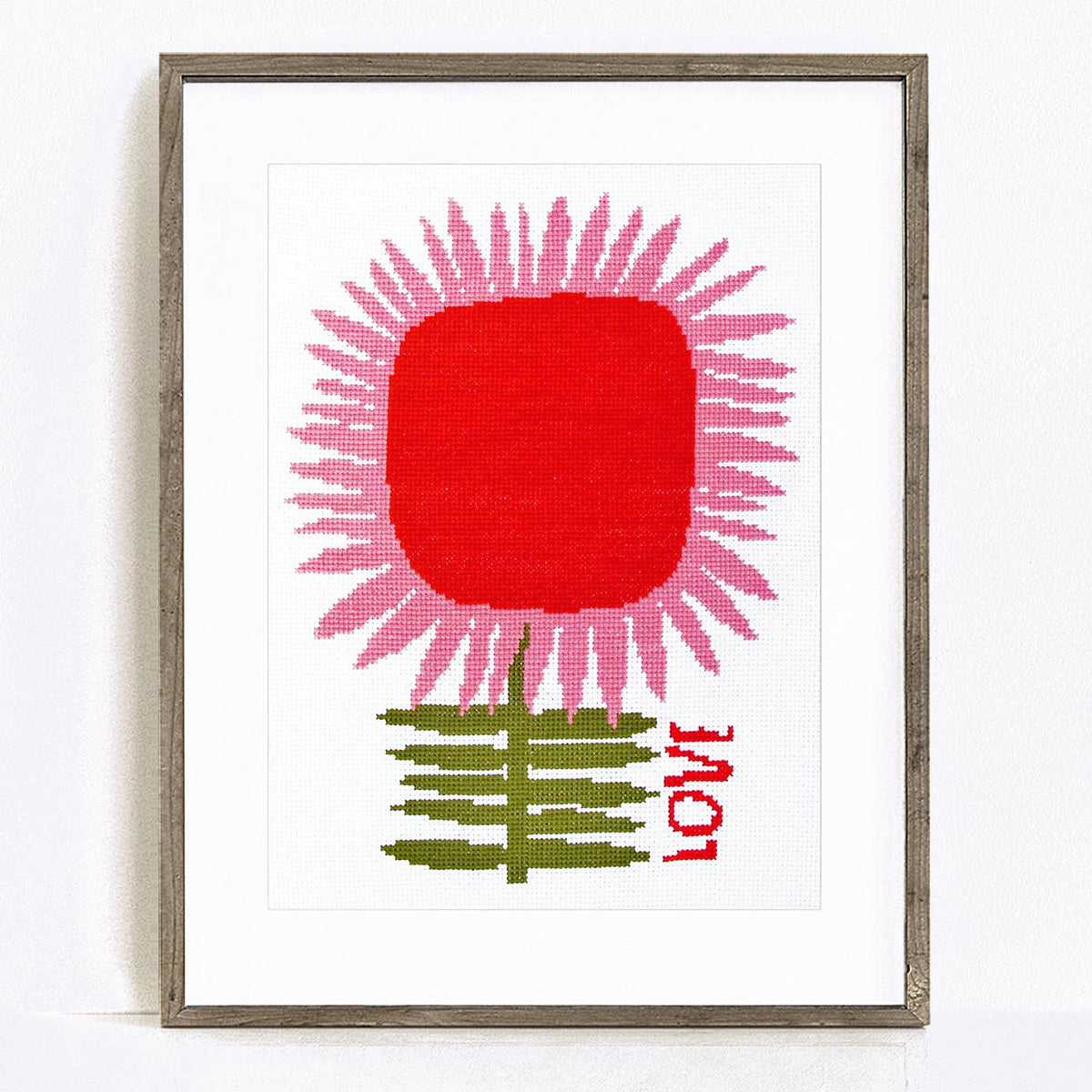 Framed artwork with a red flower and green leaves on a white background
